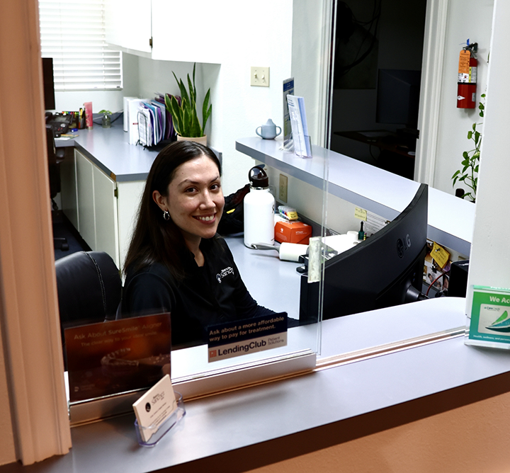 Receptionist smiling at front desk in San Antonio dental office