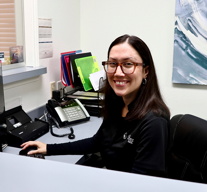 Smiling dental team member in San Antonio sitting at desk