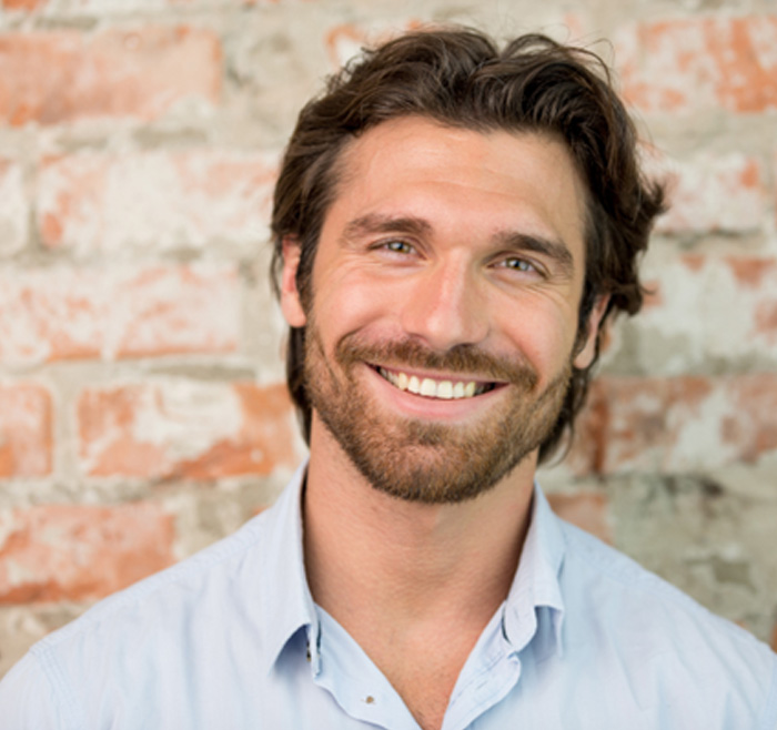 Smiling man in front of a brick wall