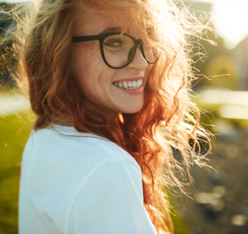 Woman with glassees smiling outside