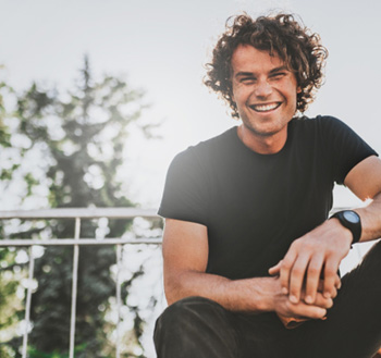 Man with watch sitting on top of bleachers and smiling