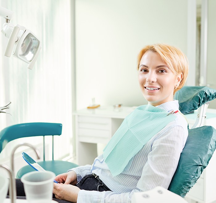 Female patient in striped shirt sitting in dental chair