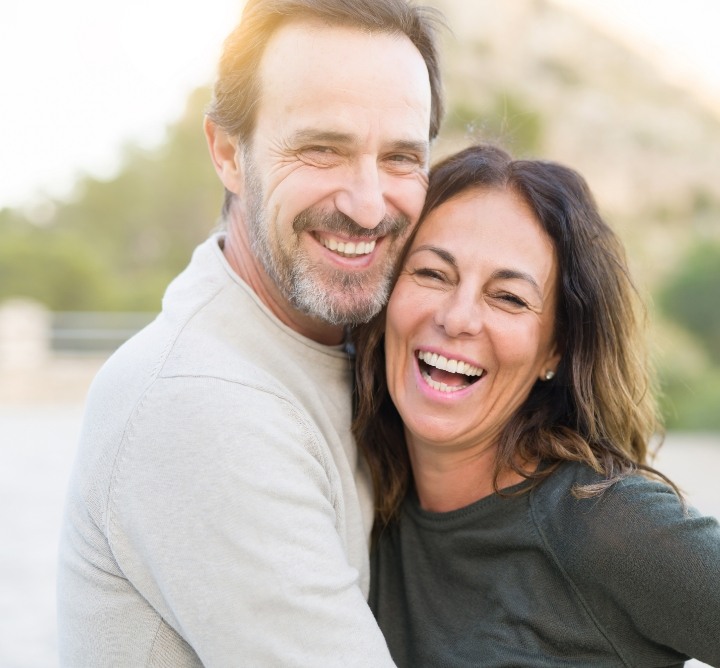 Man and woman smiling and hugging after cosmetic dentistry in San Antonio