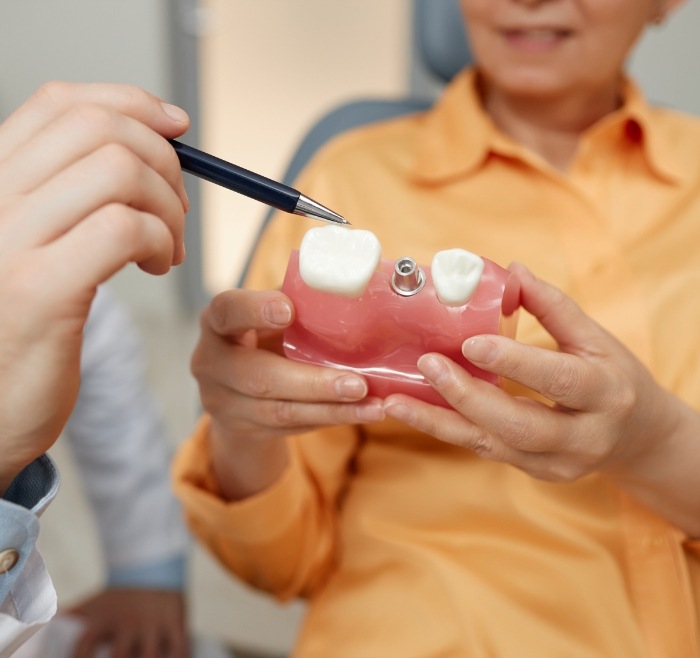 Dentist showing a model of a dental implant to a patient