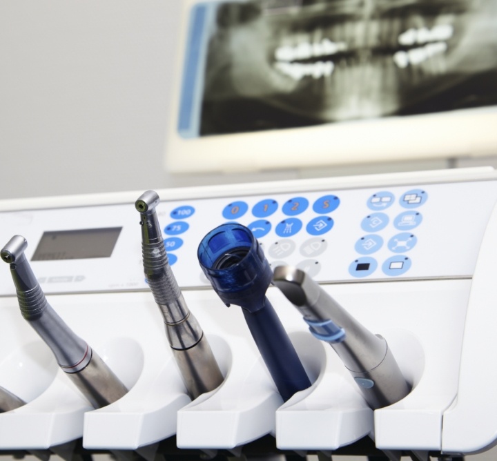 Several dental instruments with an x ray of teeth in the background