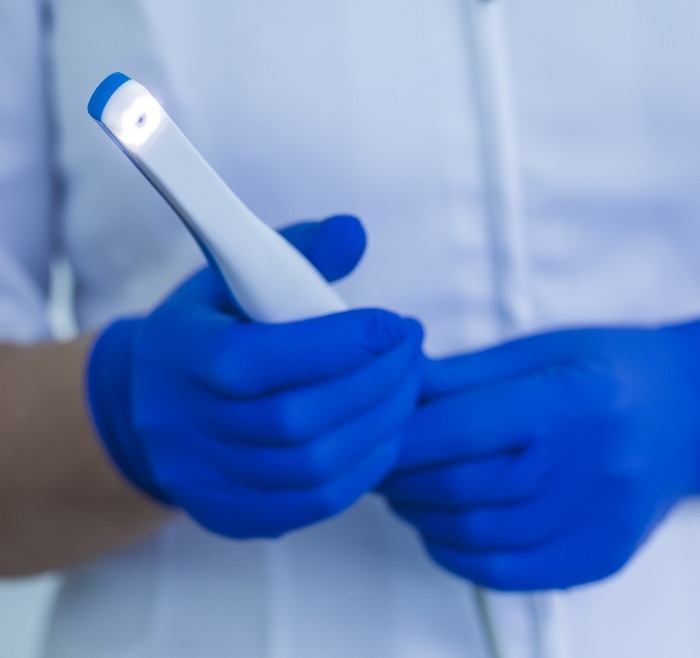 Dental professional holding a white pen like intraoral camera