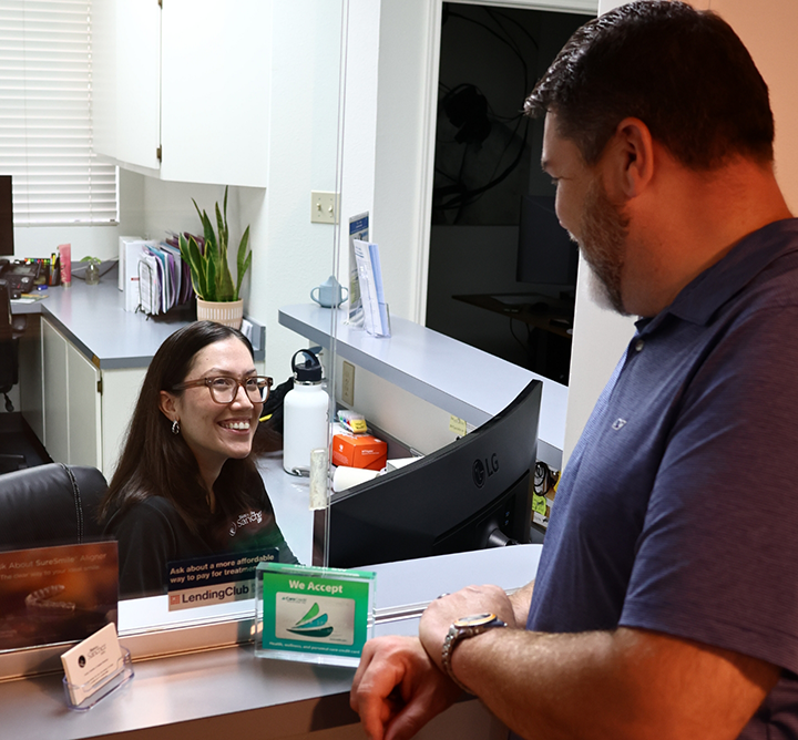 Man smiling at dental office receptionist