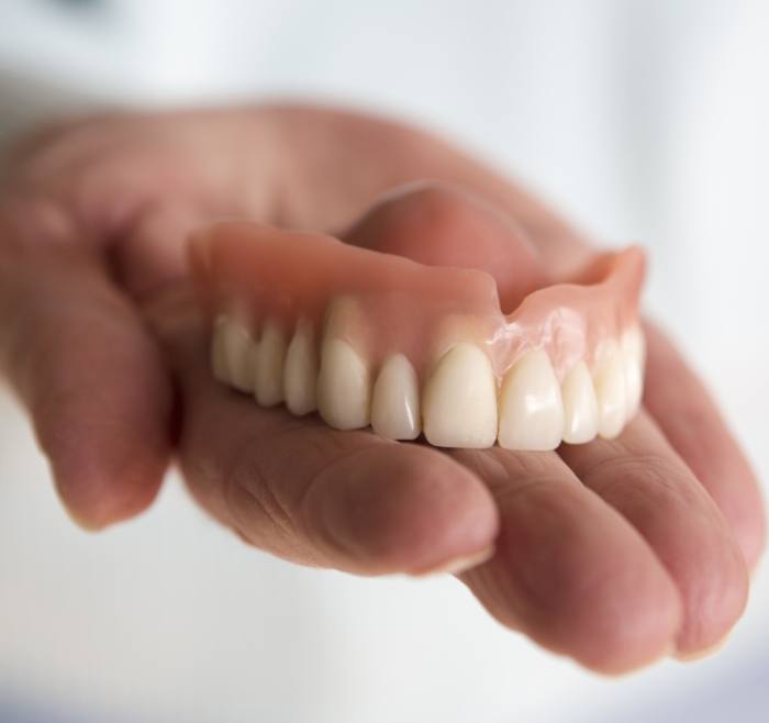 Hand holding a full upper denture