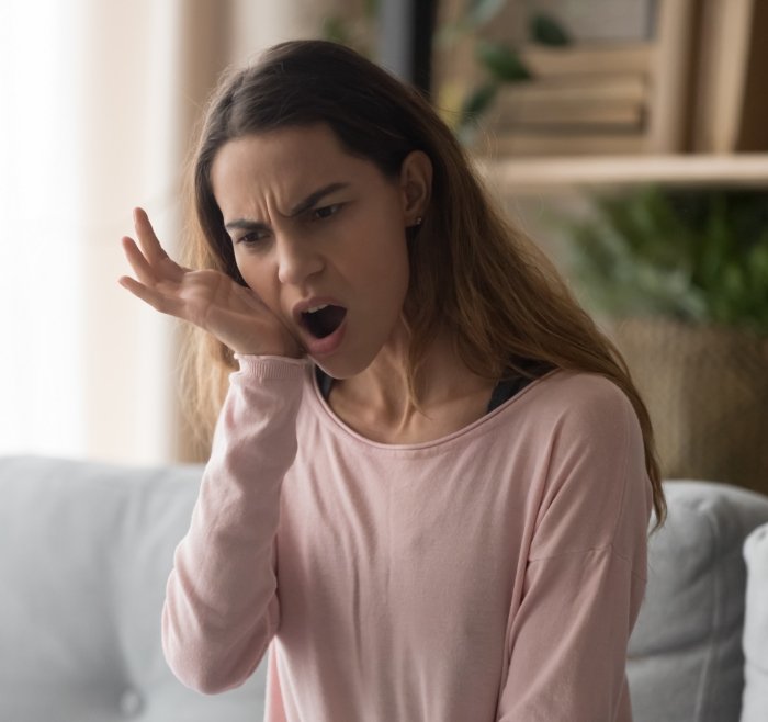 Woman holding her jaw and wincing in pain