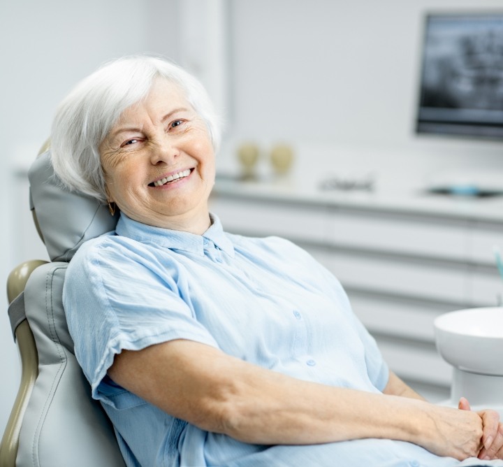 Smiling senior woman sitting in dental chair after restorative dentistry in San Antonio