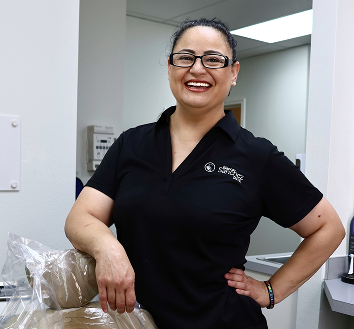 Dental team member smiling and standing next to dental treatment chair