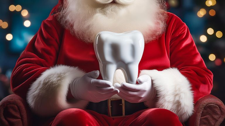 Santa Claus, dressed in his traditional red suit with white fur trim, is seated and holding a large, shiny white tooth in his hands. The background features soft bokeh lights, creating a festive atmosphere.