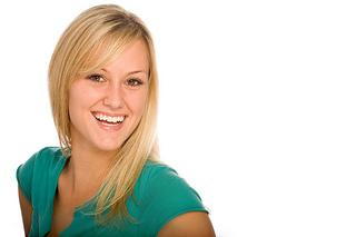 Smiling young woman with blonde hair wearing a teal shirt against a plain white background.